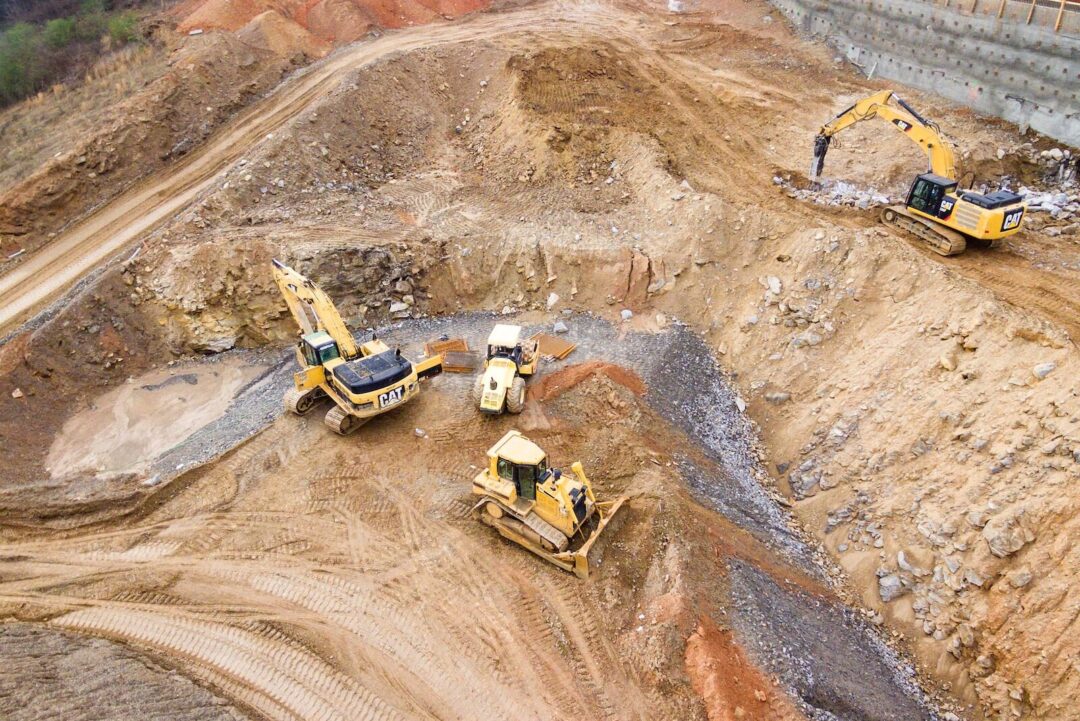 top view photography of four heavy equipment on quarry at daytime